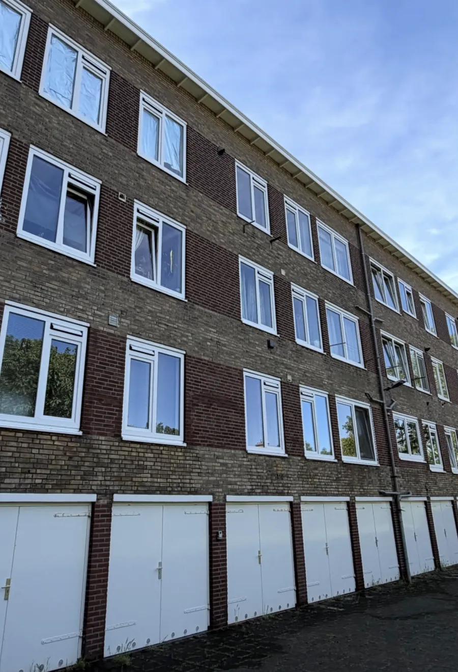 Gevel van een VvE-complex met witte kozijnen en garagedeuren